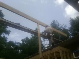 Carpenter setting a ridge beam over a new addition frame — Ice Dam Removal by Roofing Brothers in Shiro