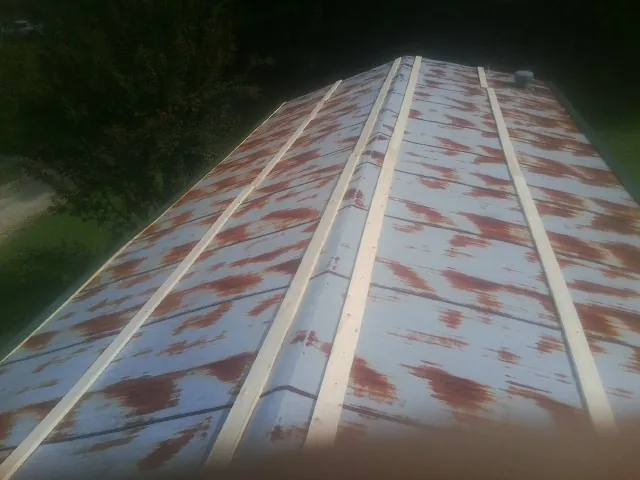Rusted metal roof panels with new wood purlins before replacement — Storm Damage Roof Repair in Shiro by Roofing Brothers