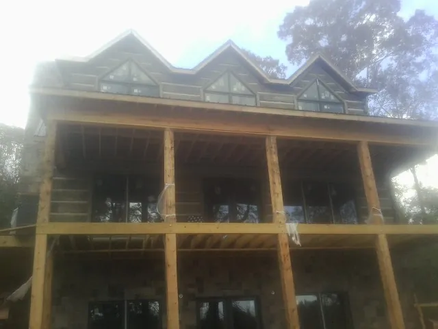 Dormers and porch framing on a large log home under construction — Roof Coating work by our crew in Shiro